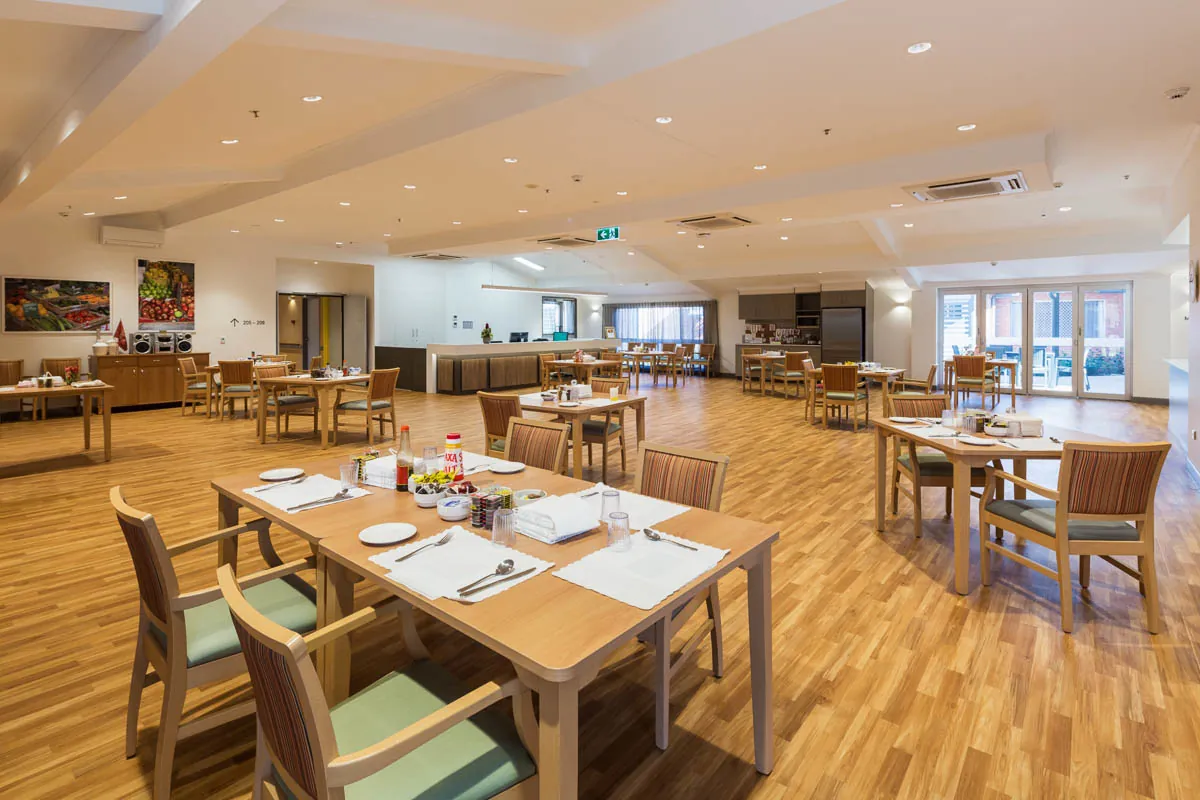 Daylit residential aged-care corridor during morning handover — calm non-incident scene