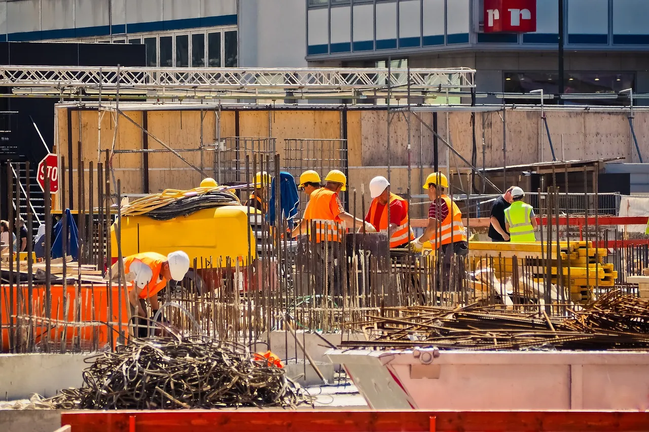 Construction workers in hi-vis vests and hard hats on an active urban building site — calm non-incident scene