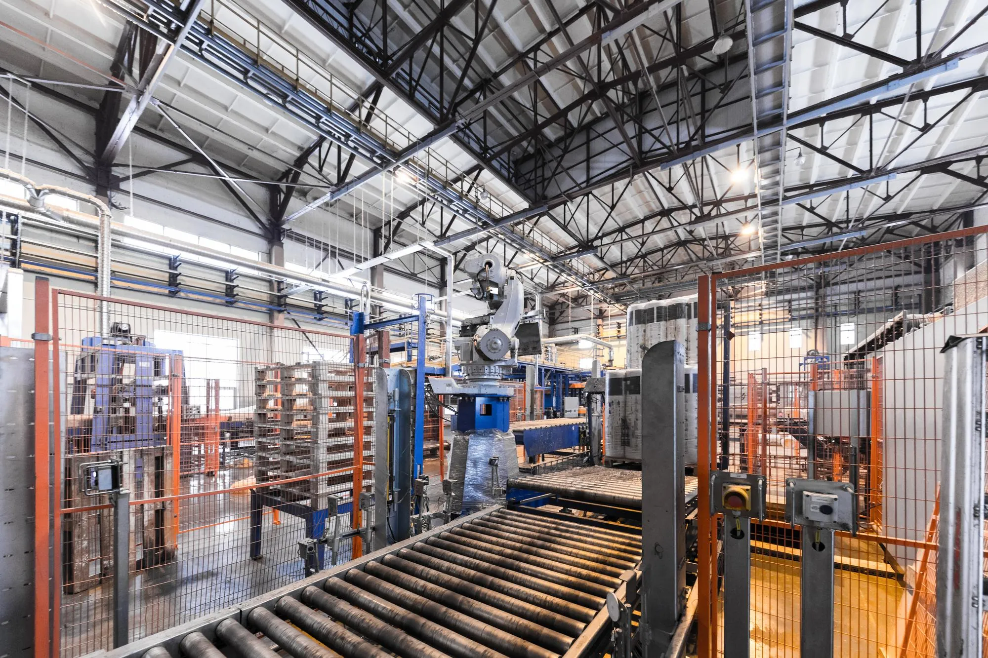Automated manufacturing floor with robotic arm, conveyor lines and safety caging — calm non-incident scene